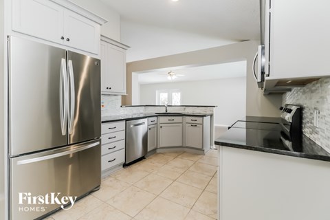 A kitchen with a stainless steel refrigerator and white cabinets.