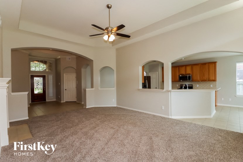 an empty living room and kitchen with a ceiling fan