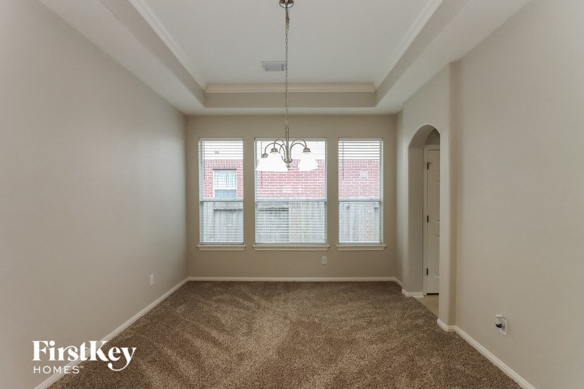 an empty living room with three windows and carpeting