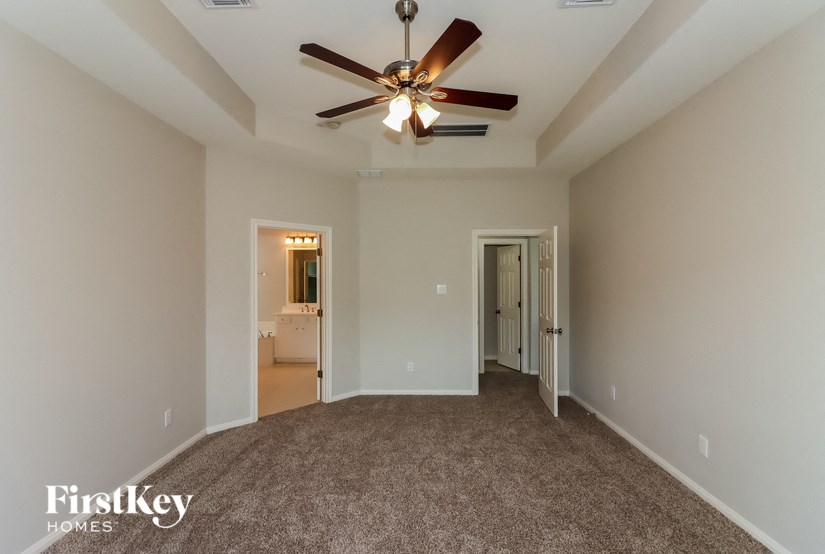 a living room with a ceiling fan and a carpet