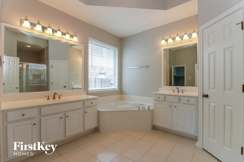 a large white bathroom with two sinks and a bath tub