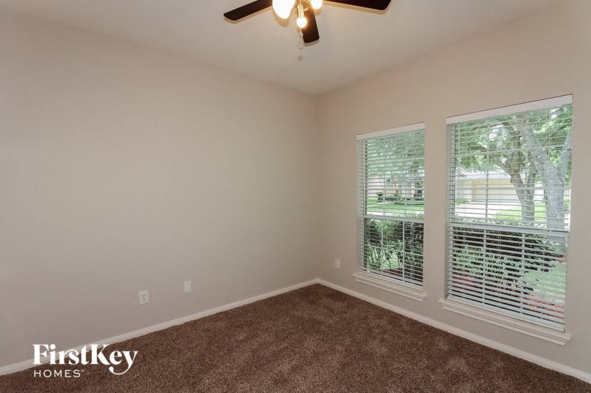 a bedroom with a window and a ceiling fan