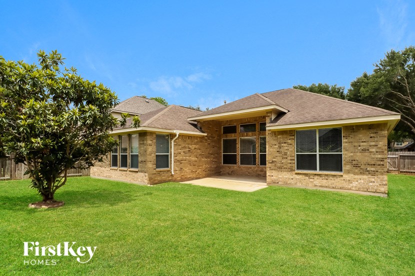 a brick house with a green lawn and a tree