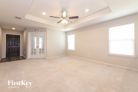 A spacious room with a ceiling fan and a door on the left.