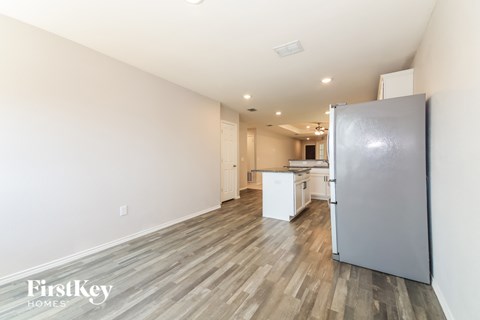 A kitchen with a refrigerator and a dining table.