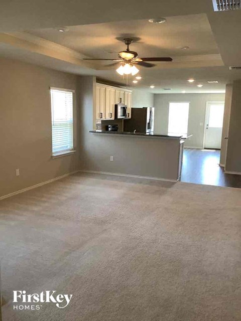 A spacious room with a kitchenette and a ceiling fan.
