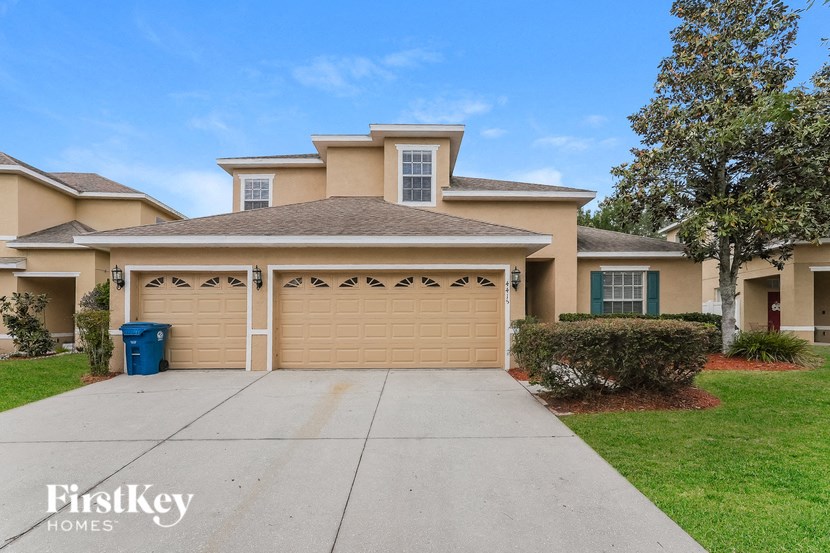 a beige house with a garage door and a driveway