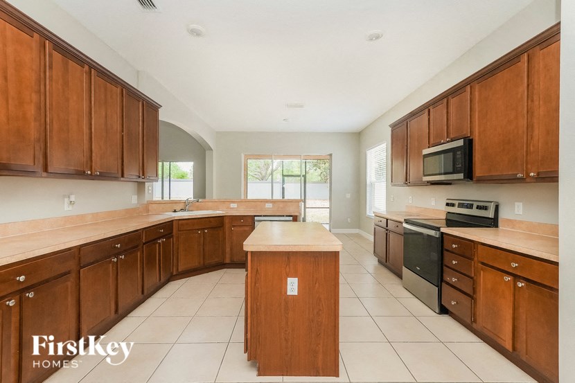 a large kitchen with wooden cabinets and tiled floors