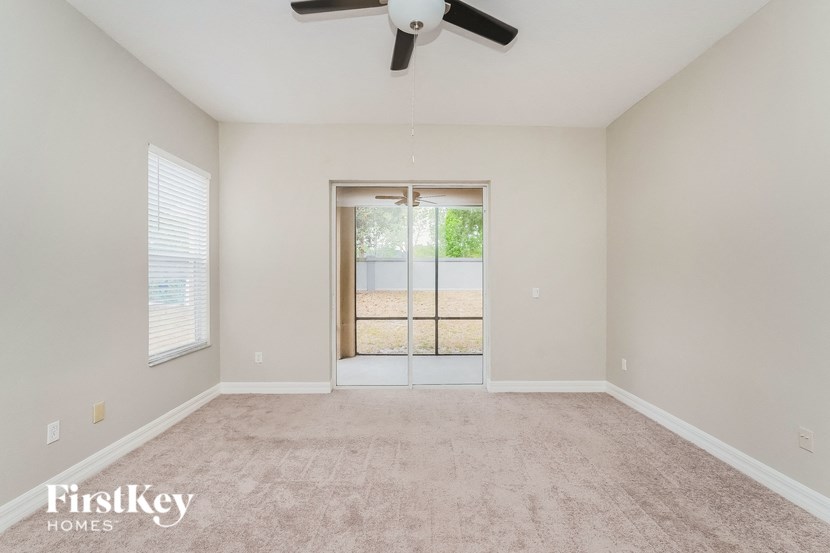 an empty living room with a ceiling fan and a window