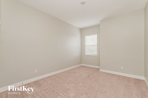 a spacious living room with beige carpet and white walls