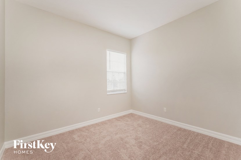 a bedroom with white walls and carpet and a window