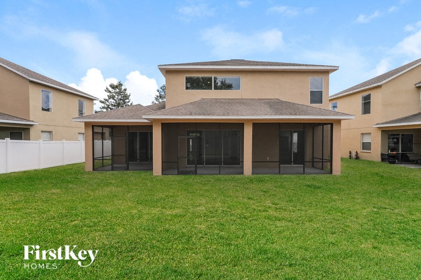 a covered patio in front of a house with a green lawn