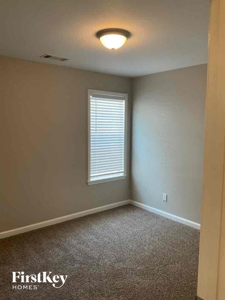 A room with a window and a carpeted floor.