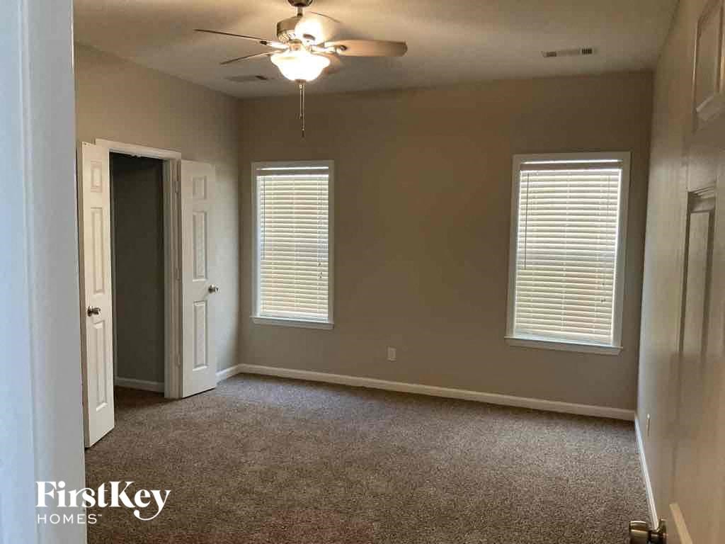 A room with a carpet floor and a ceiling fan.