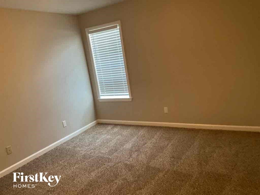 A room with a carpeted floor and a window with blinds.