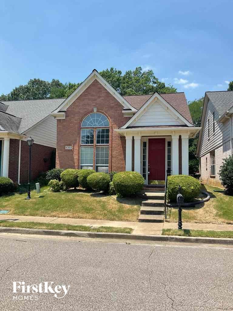 A brick house with a red door and a window with a white frame.