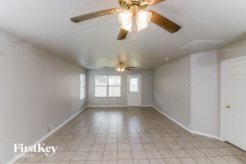 an empty living room with a ceiling fan