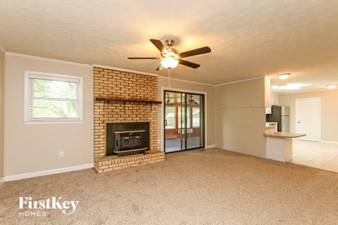 a living room with a brick fireplace and a ceiling fan