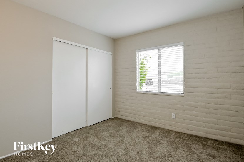 a bedroom with a window and white walls and carpet