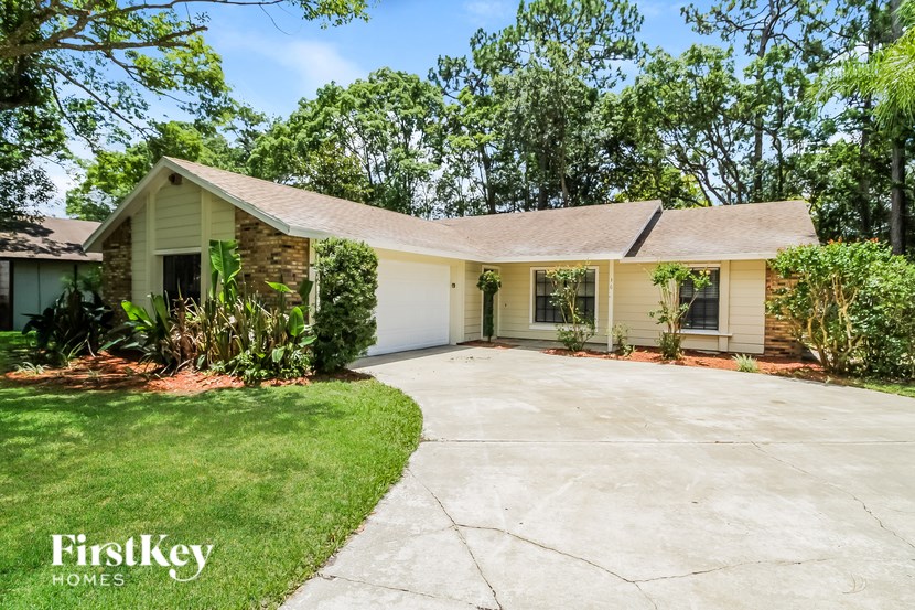 A house with a driveway and trees in the background.