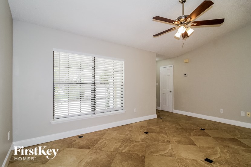 A room with a ceiling fan and a window with blinds.