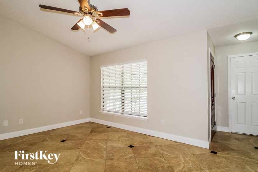 A room with a ceiling fan and a window with blinds.