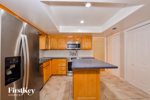 A kitchen with wooden cabinets and a stainless steel refrigerator.