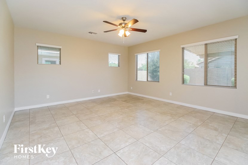an empty living room with a ceiling fan and a tiled floor