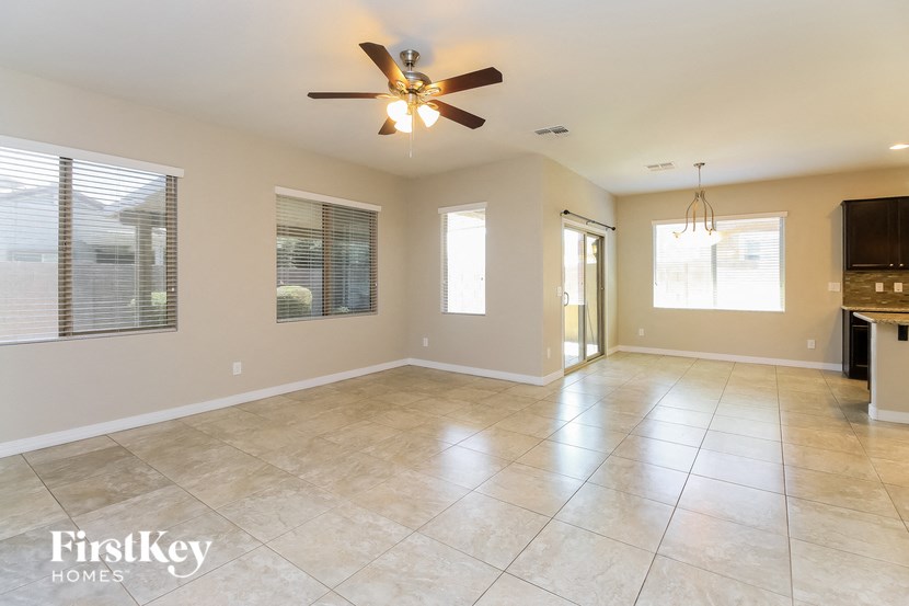 an empty living room with a ceiling fan and tile floor