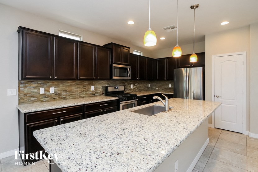 a large kitchen with granite countertops and dark wood cabinets
