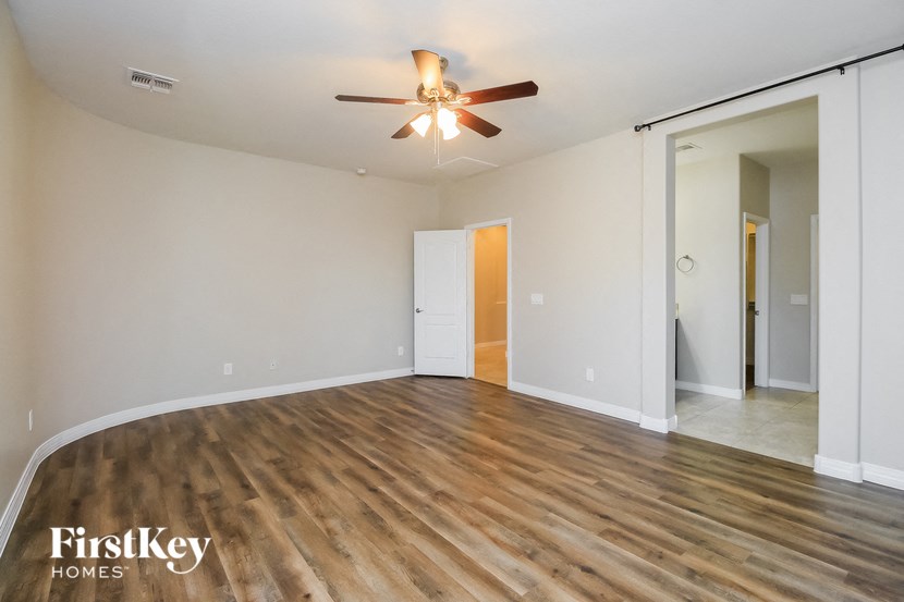 an empty living room with wood flooring and a ceiling fan