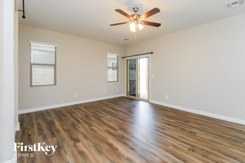 the spacious living room with hardwood flooring and a ceiling fan