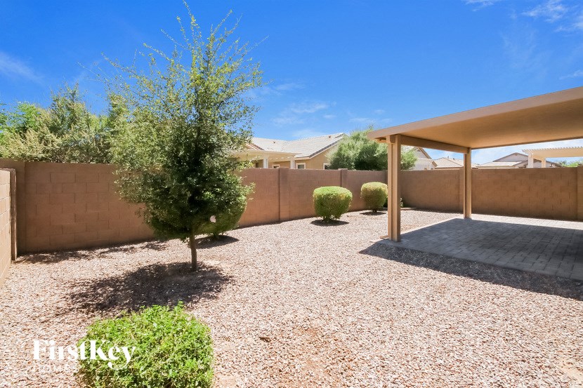 a patio with a tree and a wall with a house