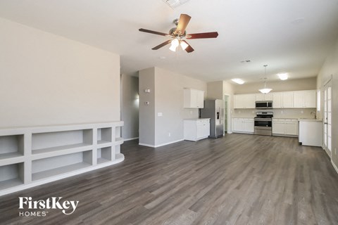 A spacious room with a ceiling fan and wooden flooring.