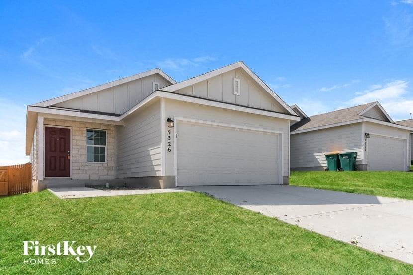 A house with a red door and a garage is for sale.