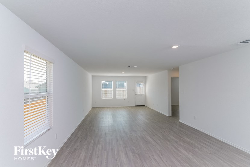 A spacious room with wooden flooring and white walls.