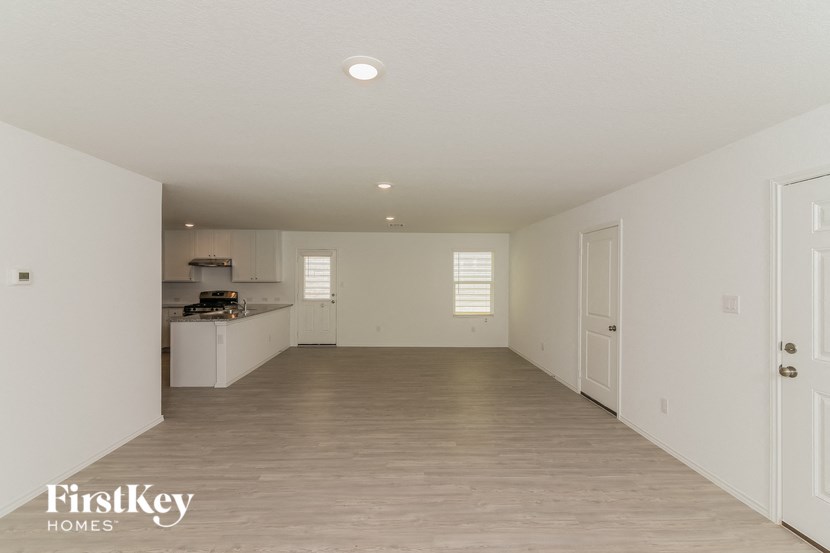 an empty living room and kitchen with white walls and wood flooring