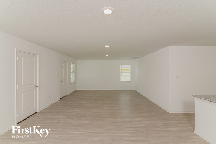 a spacious living room with white walls and wood flooring