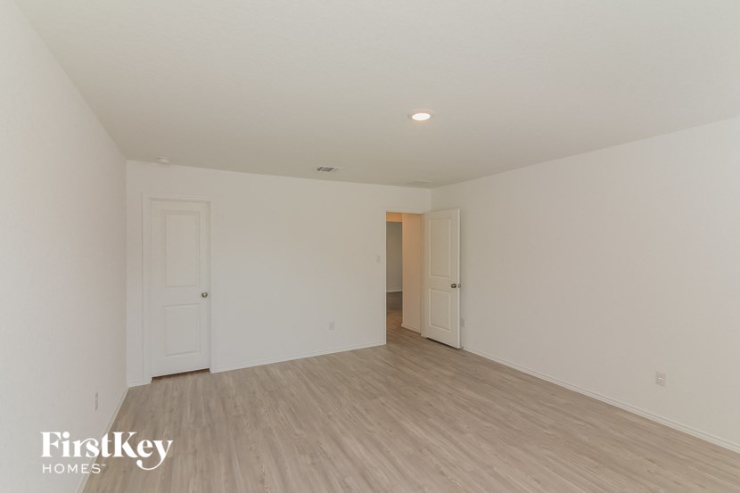a bedroom with white walls and wood flooring and white doors