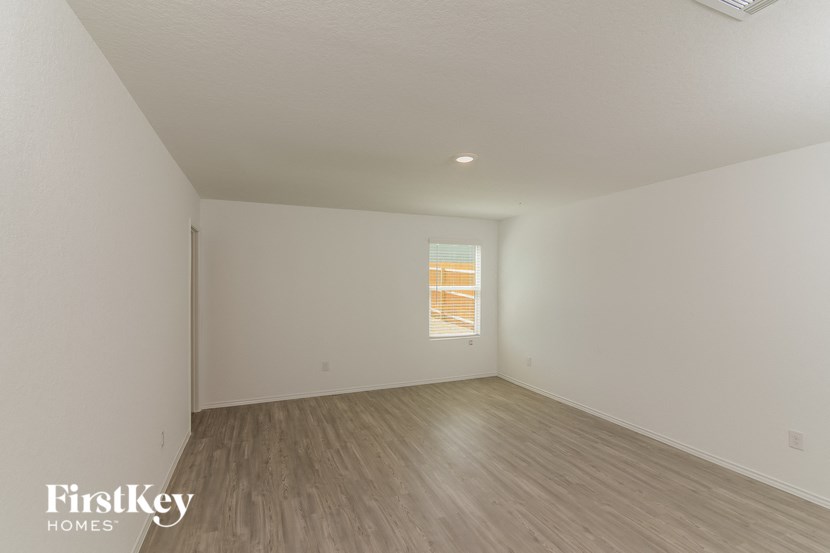 a bedroom with white walls and wooden floors and a window