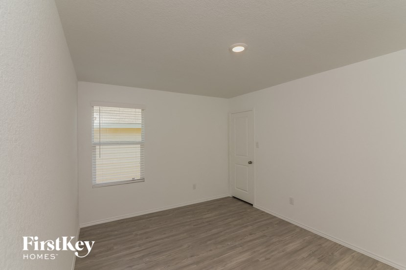 the living room of a home with white walls and wood floors