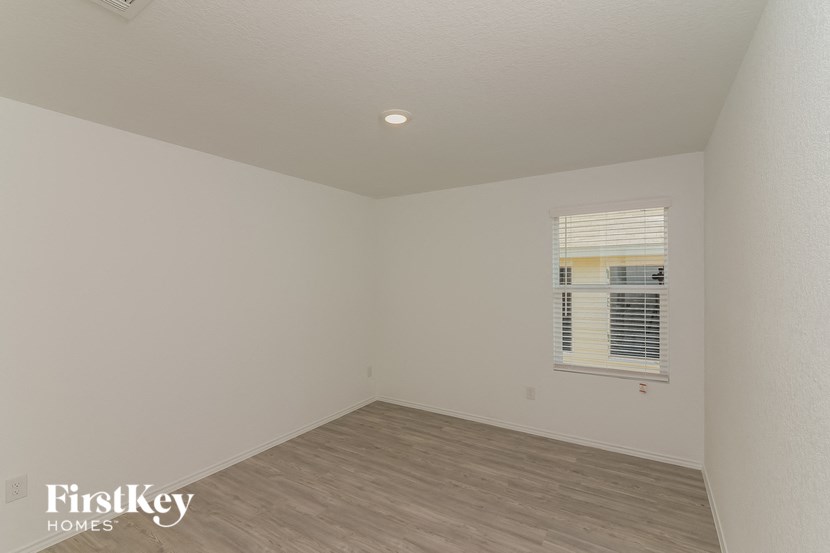 a bedroom with white walls and wood flooring and a window