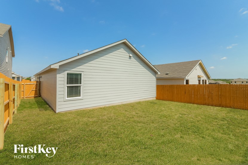 a backyard with a white house and a wooden fence