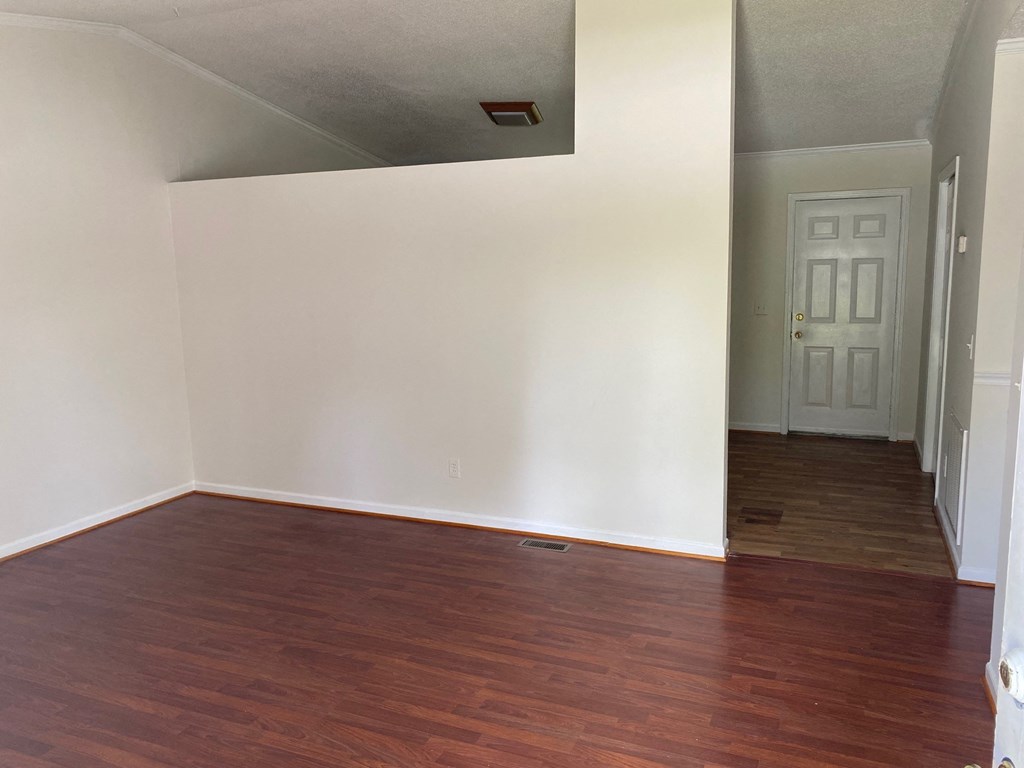 an empty living room with wood floors and a white door