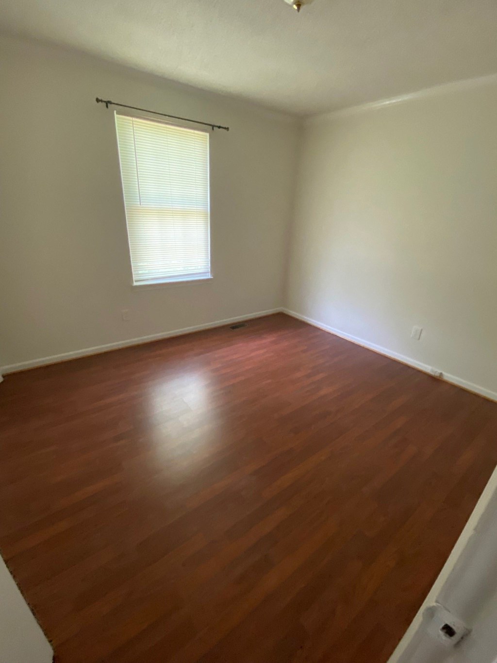 an empty room with wooden floors and a window
