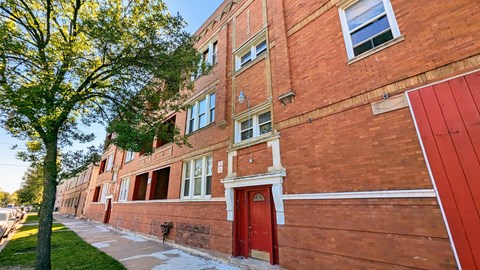 A red brick building with a tree in front of it.