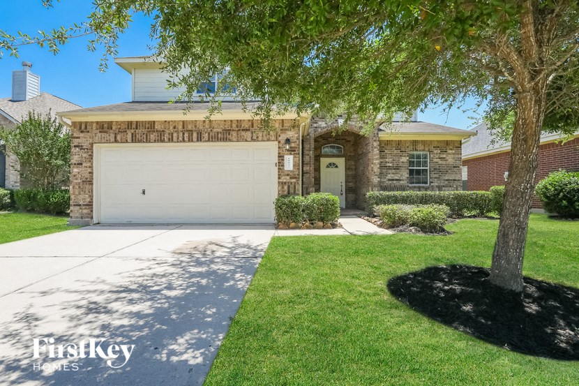A house with a garage and a tree in front.