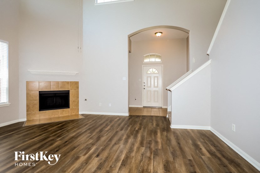 A spacious room with a fireplace and wooden flooring.