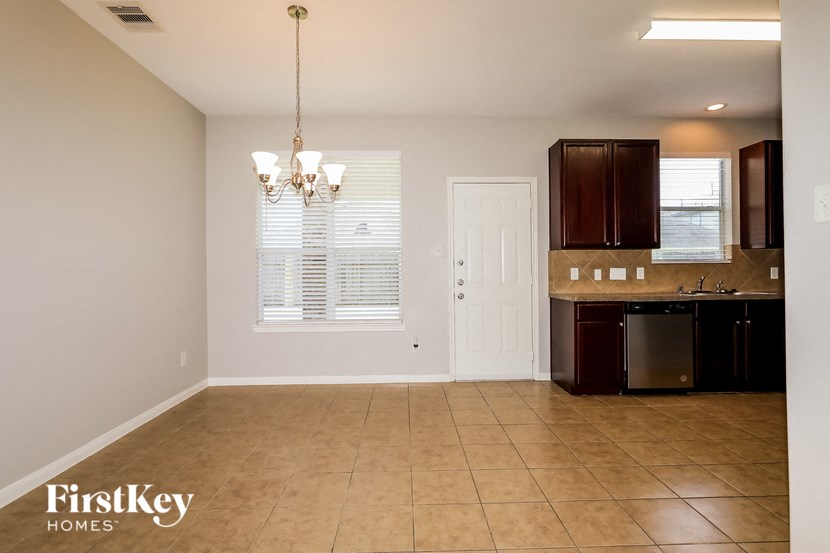 A kitchen area with a sink, cabinets, and a window with blinds.