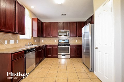 A kitchen with brown cabinets and a stainless steel refrigerator.